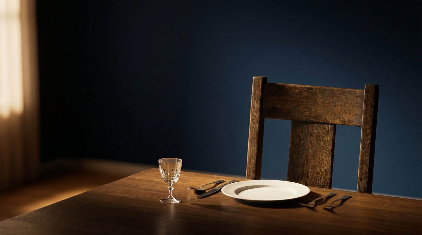 Empty chair at a family dinner table with one untouched place setting in warm light